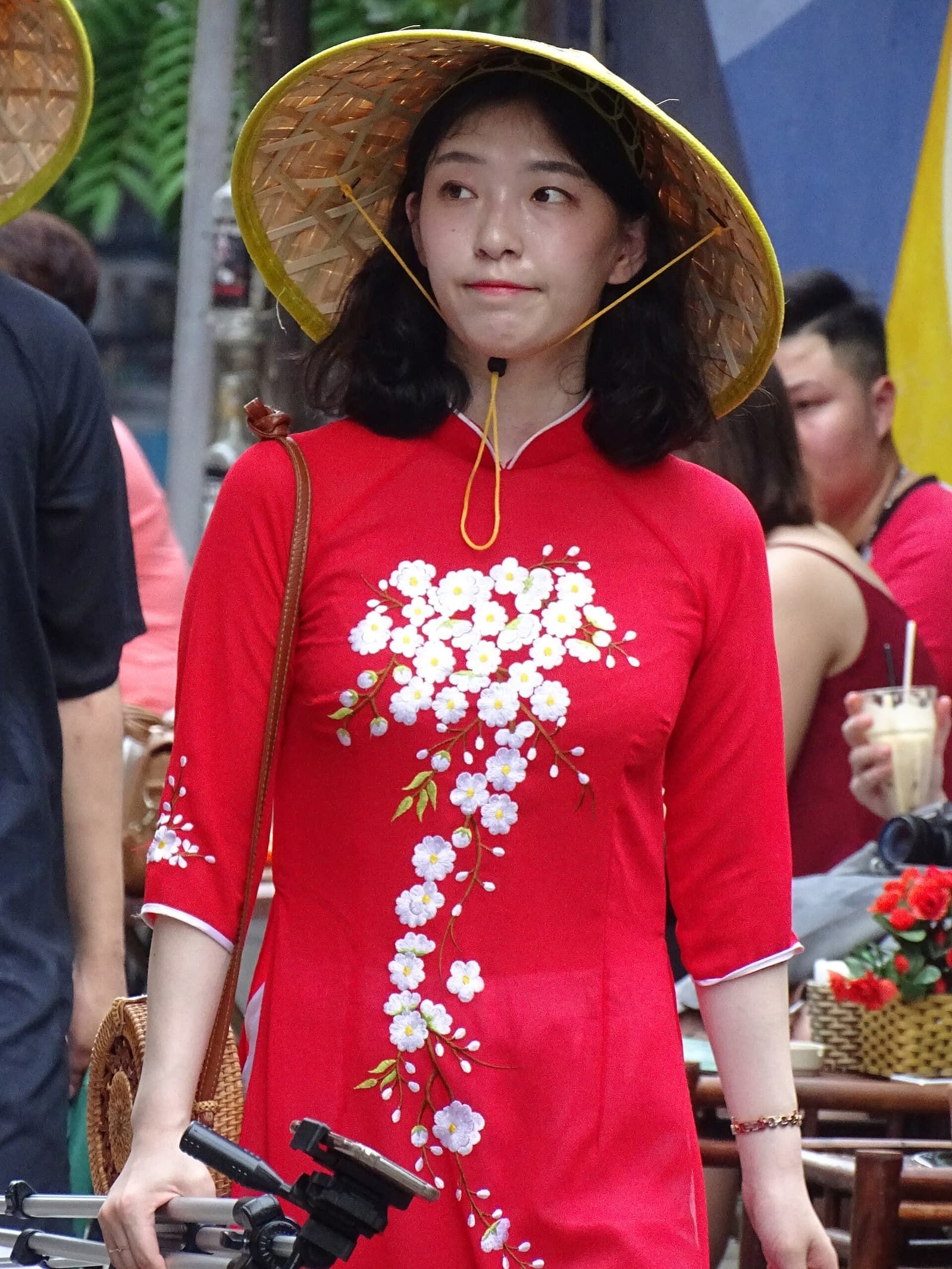 Thiếu nữ mặc áo dài đỏ, đội nón lá đi trên phố cổ Hà Nội