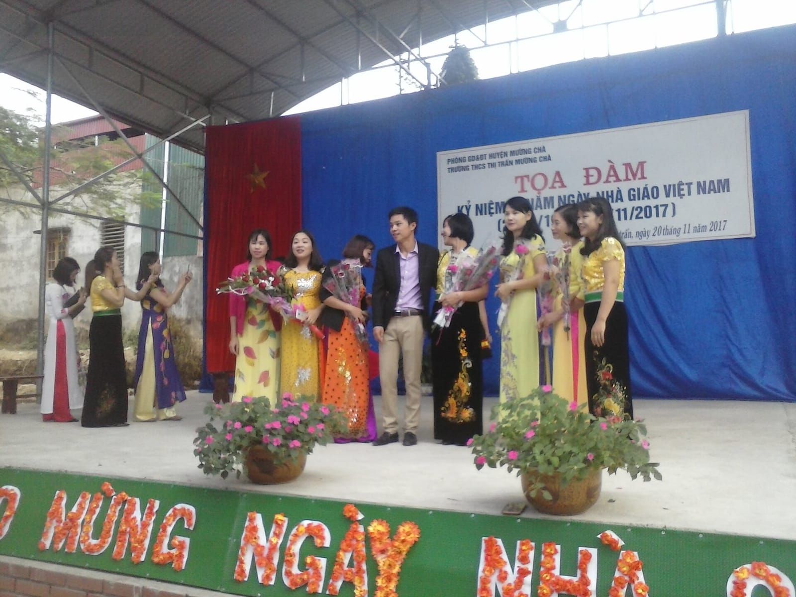 Thầy cô mặc áo dài cầm hoa chụp ảnh kỷ niệm tại lễ kỷ niệm Ngày Nhà giáo Việt Nam 20/11