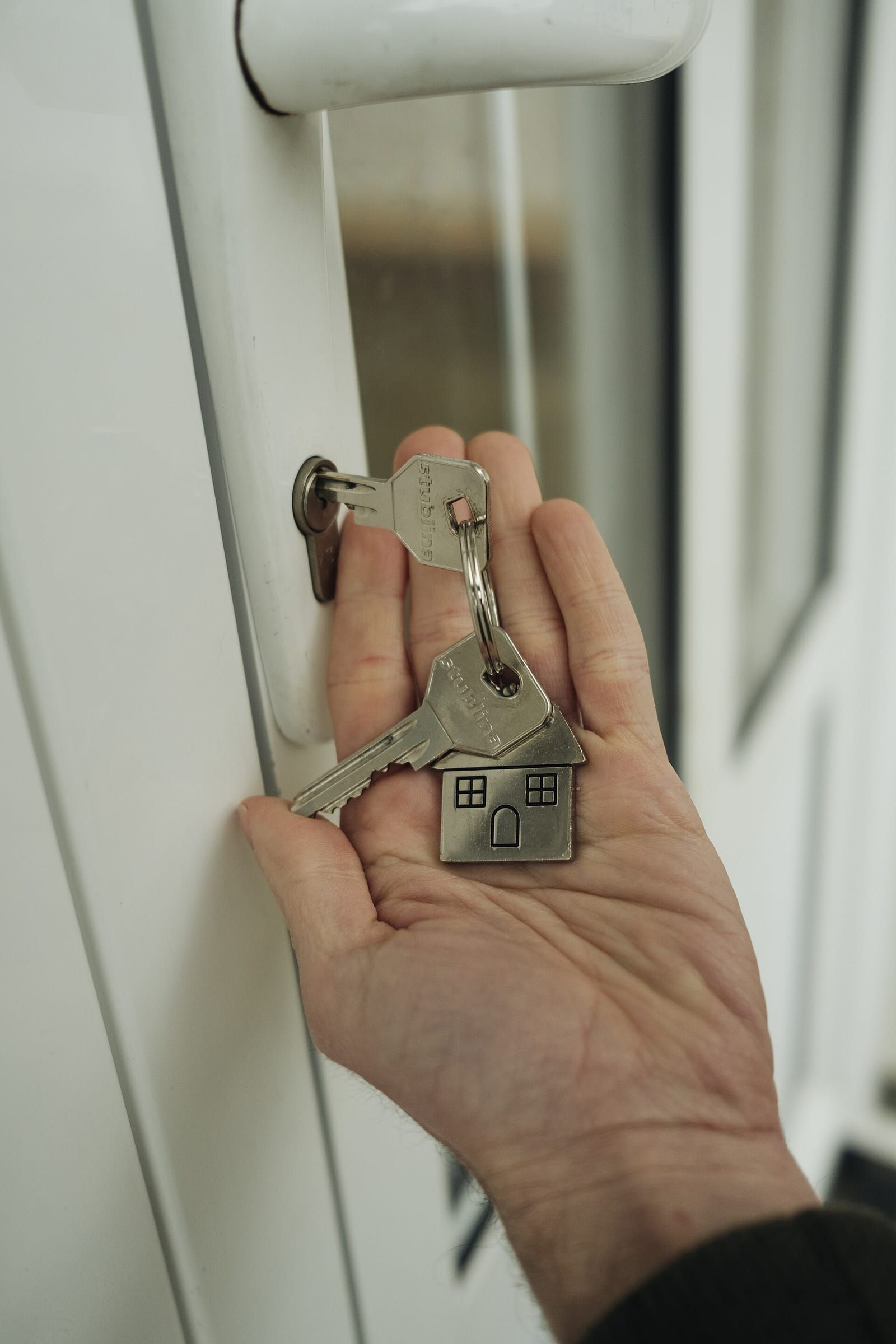 Bàn tay cầm chùm chìa khóa tra vào ổ khóa cửa — khoảnh khắc về nhà mới